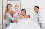 Happy man pointing the camera while being surrounded by his family and a doctor
