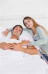 Relaxed patient and his wife holding hands in a hospital bedroom