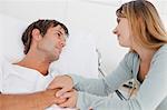 Couple in love holding their hands in a hospital bedroom while looking at each other