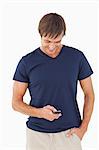 Relaxed young man sending a text while standing upright with his hand in his pocket