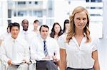 Brunette haired woman looking in front of her while standing with her colleagues behind her