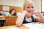 Sourire de petite fille assise au bureau en classe