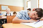 Tired elementary student taking a rest at his desk