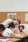 Side view of smiling elementary teacher helping a student