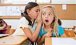 Little Schoolgirl erzählen ihre Schulkameradin ein Geheimnis
