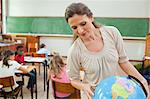 Elementary teacher looking at globe in classroom