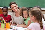 Smiling elementary teacher painting together with students