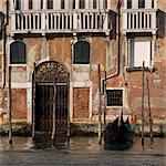 Gondola moored on Venice building exterior.