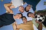 Boy (13-15) with brothers and father in huddle, view from below.