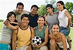 Group of people in park with woman holding soccer ball.