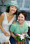 Mother and daughter with flowers, outdoors, (portrait)