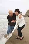 Mature couple playing in surf on beach