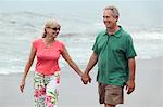 Couple holding hands, walking on beach