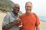 Two men with American football on beach, (portrait)