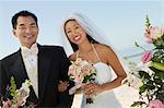 Bride and Groom with flowers on beach, (portrait)