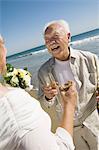 Senior newly weds toasting champagne at beach