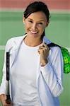 Femme avec des balles de tennis et permanent de la raquette sur le court de tennis, portrait