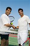 Tennis Players shaking hands over net on court, portrait