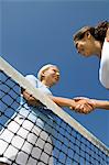 Two female Tennis Players shaking hand over tennis court net, low angle view
