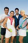 Four mixed doubles tennis players by net at tennis court, portrait