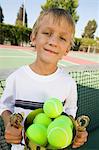 Junge am Tennisplatz Holding Trophy gefüllt mit Tennisbälle, Porträt