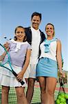 Family on Tennis Court standing by net, portrait, low angle view