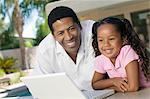 Father and Daughter Using Laptop on patio, portrait