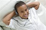 Boy lying on sofa Listening to Music on Headphones, portrait, overhead view