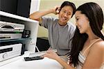 Couple sitting next to Home Theatre System, man listening on headphones, close up