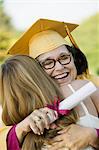 Middle-aged graduate hugging daughter outside