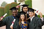 Graduates hoisting diplomas outside, portrait