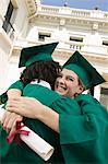 Two graduates hugging outside university