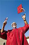 Senior graduate tossing hat in air outside, low angle view