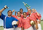 Girls' soccer team (13-17) holding trophy and celebrating, portrait