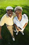 Senior couple on golf course, smiling, (portrait), (elevated view)