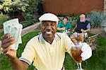 Senior golfers celebrating success, focus on man showing banknotes, (portrait)