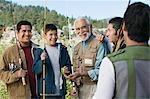 Male members of three generation family holding fishing rods outdoors, smiling