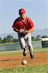 Baseball fielder running towards ball on ground