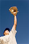 Baseball player catching ball in baseball glove, (low angle view)