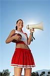 Cheerleader Holding Football and Megaphone, low angle view, portrait, (portrait), (low angle view)