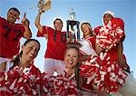 Football players and cheerleaders hoisting trophy, low angle view, portrait, (portrait)