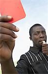 Arbitre de soccer miroiter carton rouge et sifflet gonflant, portrait