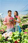 Young couple choosing potted flowers in garden centre