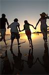 Familie läuft durch Meer bei Sonnenuntergang, hintere Ansicht, Kontur