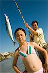 Homme montrant des poissons pour fille (7-9) à l'océan