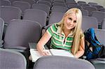 Female student sitting alone in lecture hall, (portrait)
