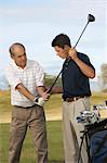 Young Man Helping Man with Grip on Golf Club on golf course