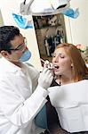 Dentist examining young womans teeth in surgery