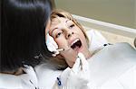 Dentist examining female patient in surgery