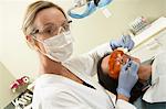 Dentist examining female patient in surgery, (portrait)